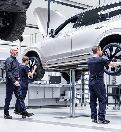 Technicians working on a Volvo raised on a workshop lift
